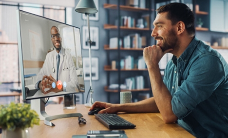 Man sitting at home talking to a doctor on his computer monitor