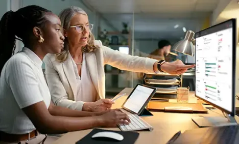 2 women working at a monitor and tablet computer