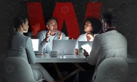people meeting around a conference table with open laptops
