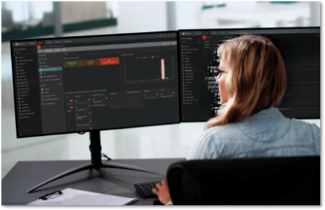 Woman sitting in front of two mionitors in dark mode