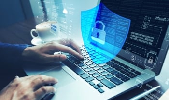 Person typing on a laptop with a transparent digital shield and lock icon overlay, representing cybersecurity, data protection, and secure online access.