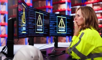 Warehouse worker reviews multiple monitors displaying system hacked warnings, representing cyberattacks targeting logistics and supply chain operations.