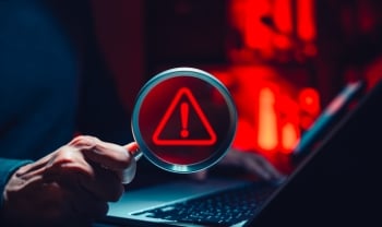 Cyber threat detection and data risk warning concept. Person holding magnifying glass with digital alert symbol representing cybersecurity breach, malware investigation, system vulnerability analysis.