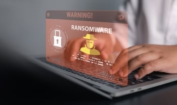 Businessman using laptop with ransomware warning alert and hacker icon. Concept of cyber attack, malware infection, data encryption threat, network security breach, and digital protection.