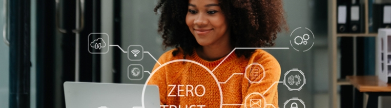 A professional woman works on her laptop in a modern office, with a digital overlay reading “Zero Trust.” The image represents secure, identity-based remote access and the shift from traditional VPNs to Zero Trust Network Access.
