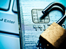 Open padlock sitting on top of a credit card and a keyboard
