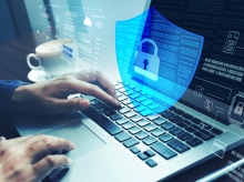 Person typing on a laptop with a transparent digital shield and lock icon overlay, representing cybersecurity, data protection, and secure online access.
