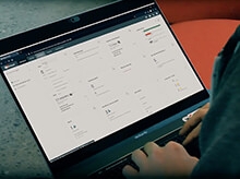 Video screenshot of a person using a laptop showing a WatchGuard Cloud screen