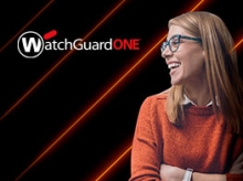Blond woman in an orange sweater smiling at the WatchGuardONE logo