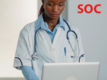 Black woman in a doctor's coat with a stethoscope around her neck working on a laptop