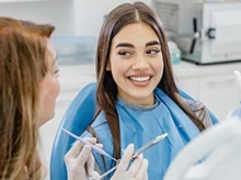 Dental technician talking to a patient in a blue paper bib