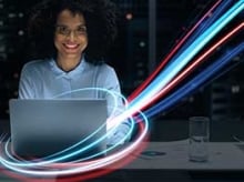 Smiling business woman in front of a laptop with colored lights circling it