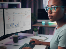 woman working at a computer with WatchGuard Cloud dashboards on the screen