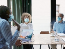 Masked workers sitting around a conference room table