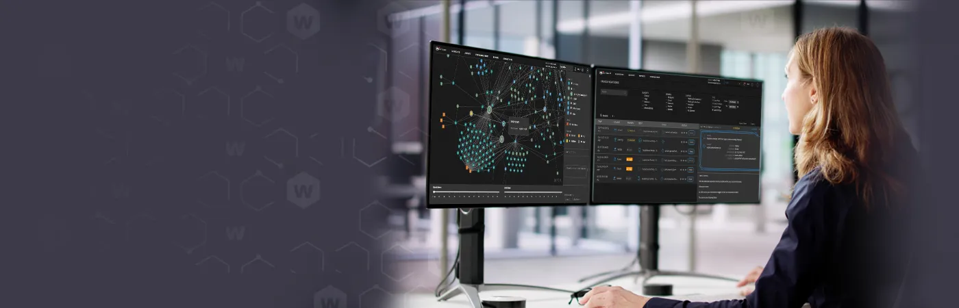blonde woman working at two monitors showing WatchGuard MDR dashboards
