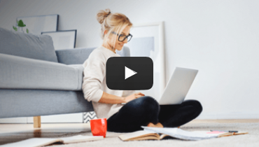 Woman sitting in front of her couch working on a laptop
