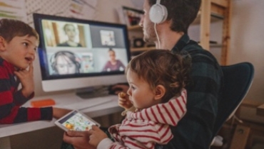 man on a virtual meeting with two children next to him