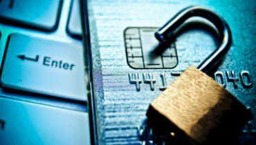 Open padlock sitting on top of a credit card and a keyboard