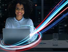 Smiling business woman in front of a laptop with colored lights circling it