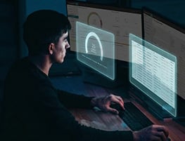 Man working at double monitors in a darkened office