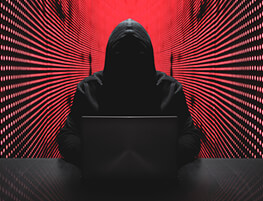 Shadowy figure at a laptop with a red glow and lines behind them